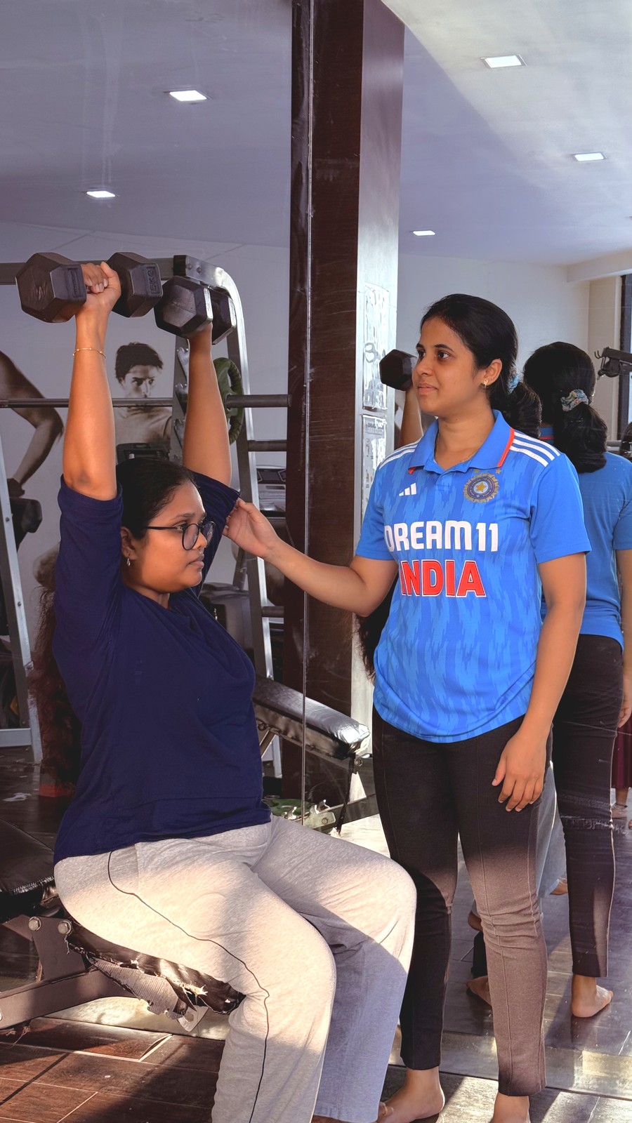 Nandhini training a client with dumbbells